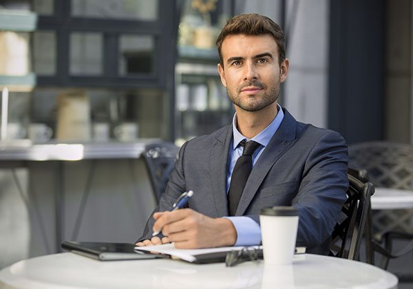 Portrait of young handsome entrepreneur working outside cafe